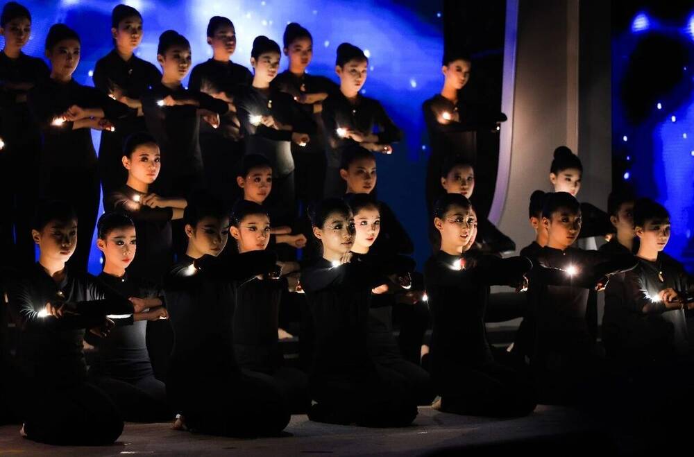 The children's choir in black, each holding a small light, singing in five languages