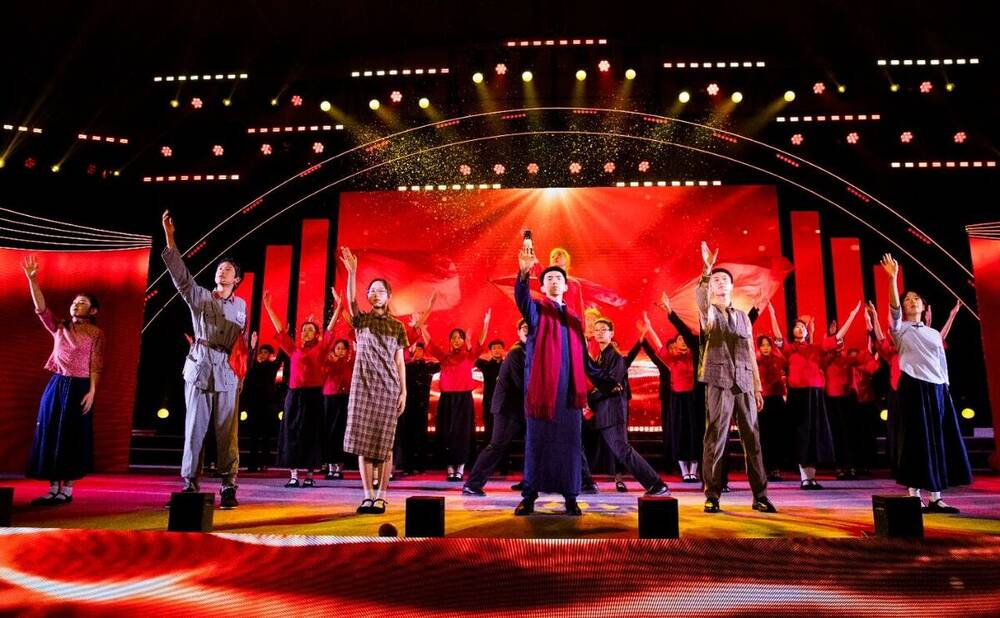 Students performing a musical theatre number on a stage with a red backdrop