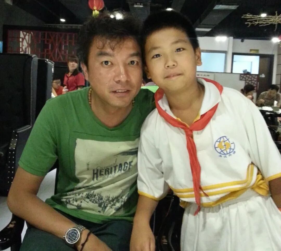 A father and his young son smiling together at a table in a canteen