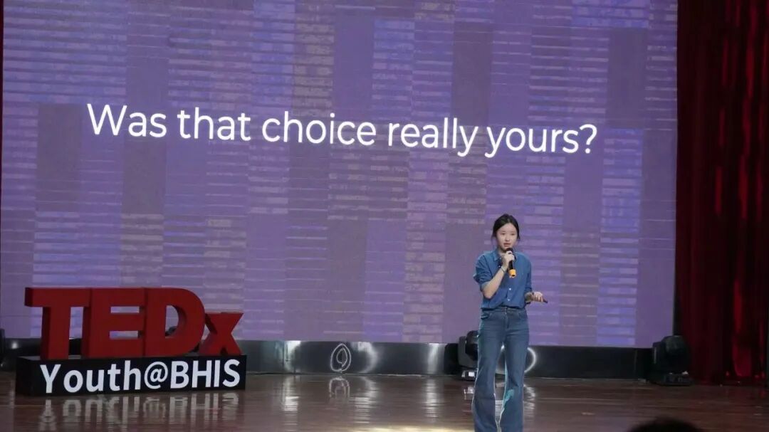 Zhou Zhuoyi on stage at a TEDx event, with a slide behind her reading Was that choice really yours?
