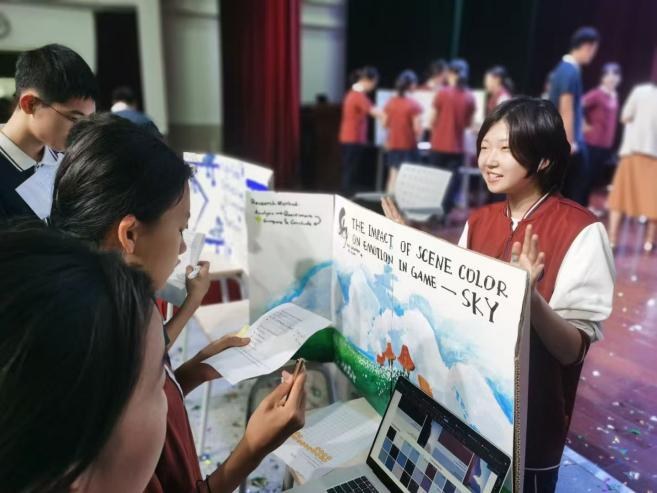 A student presenting a poster on the impact of scene color on emotion in games to two visiting peers