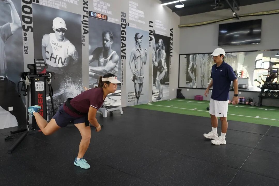 A player working with a fitness coach in the campus gym