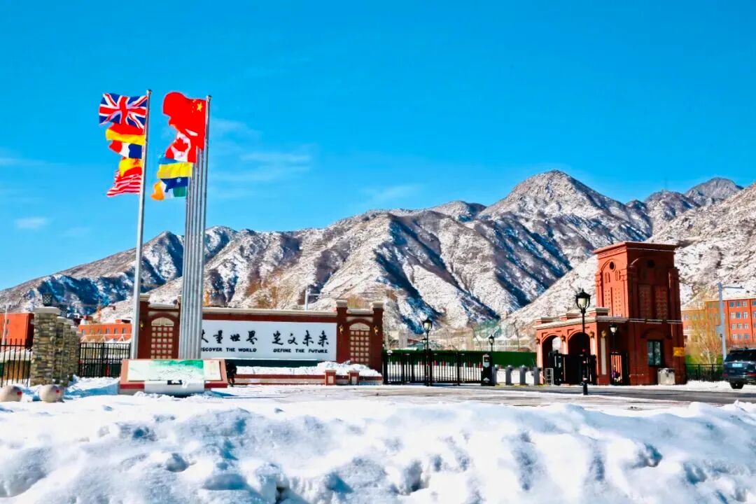 The campus gate in winter, with snow-covered mountains behind