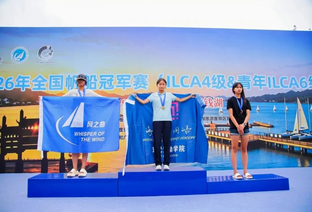 The podium at Dongqian Lake with three sailors holding team flags