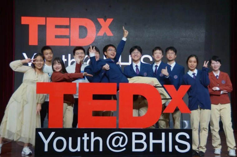The 2023 TEDx Youth@BHIS team posing with the TEDx sign on stage