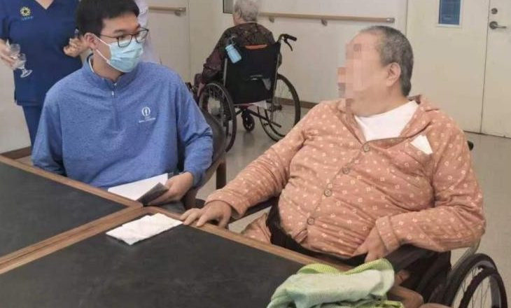 A student sitting with an elderly care-home resident